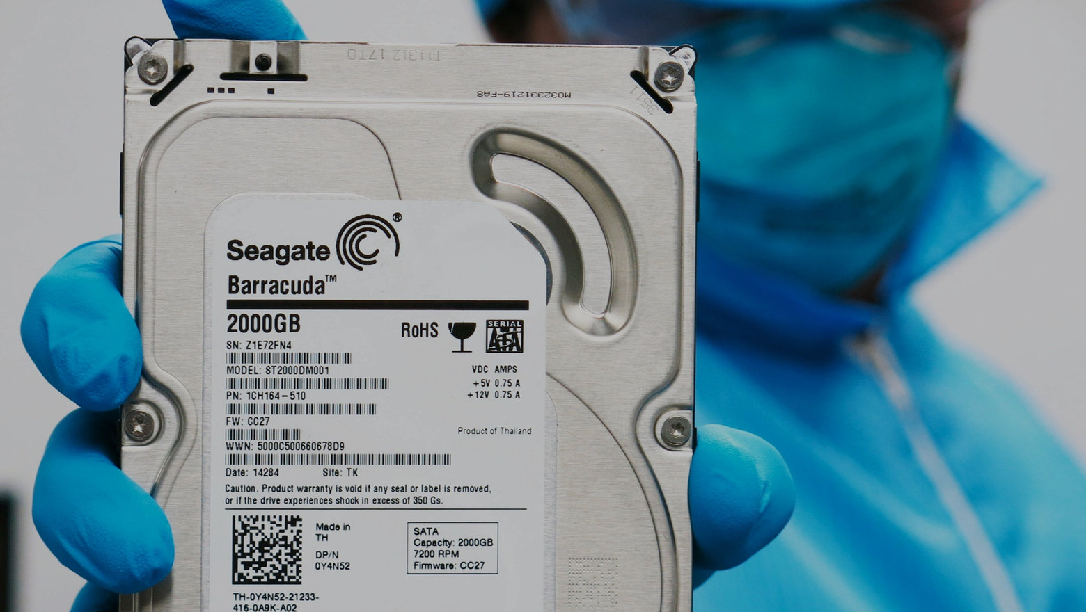 Técnico de +DR Data Recovery sosteniendo un disco duro Seagate Barracuda en sala limpia